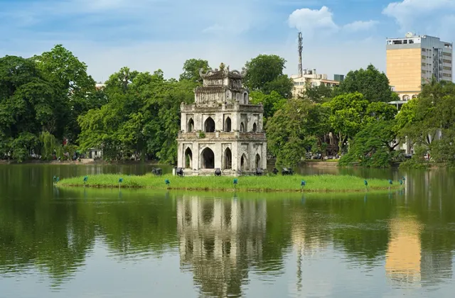 A stone pagoda on a small island in a lake surrounded by trees
