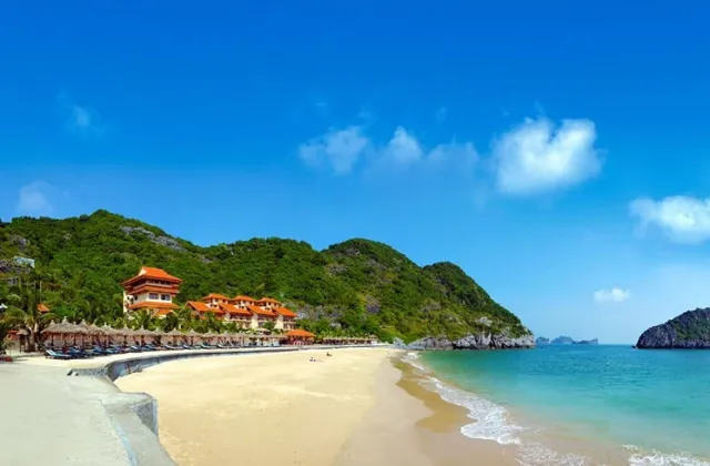 A sandy beach with a hillside temple and turquoise sea