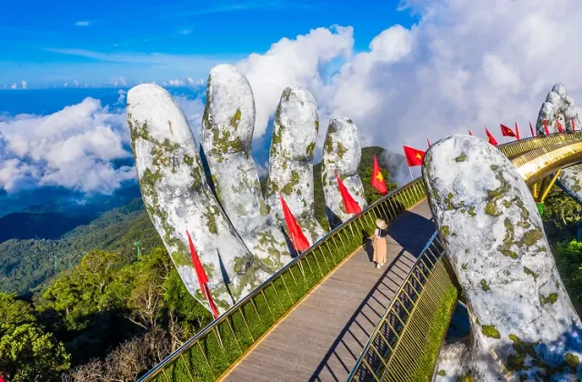 A golden footbridge held by two giant stone hands above the clouds