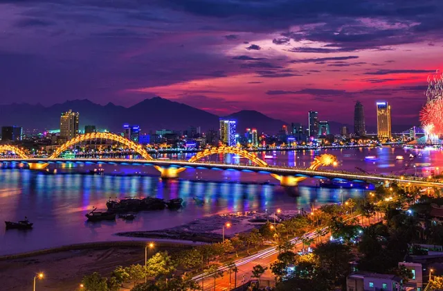 An illuminated bridge over a river city at dusk